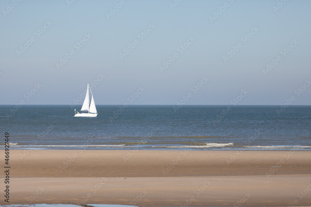 Obraz premium sailboat on the sea, beach in the foreground, blue sky