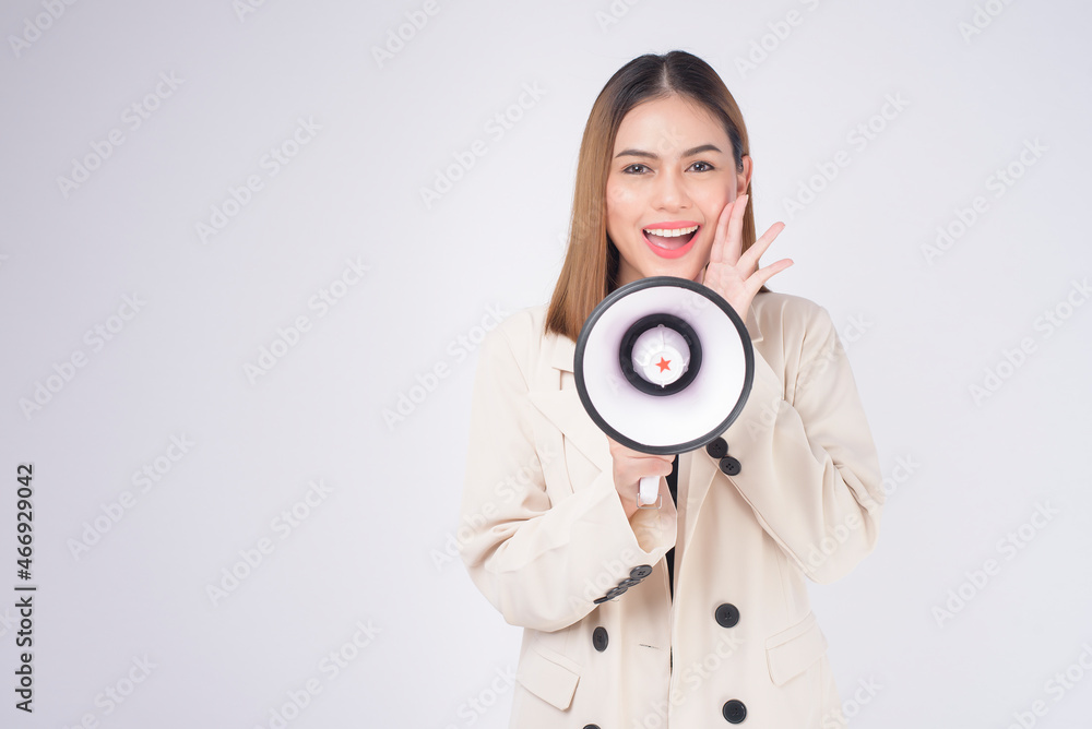 Fototapeta premium portrait of young beautiful smiling woman in suit using megaphone to announce over isolated white background studio..