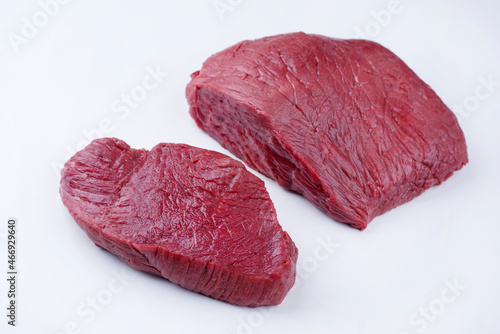 Raw dry aged bison beef rump steak slices offered as close-up on white background with copy space - free-form select photo