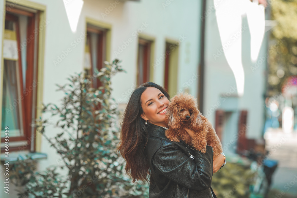 A young beautiful woman with her poodle dog is walking in a European city. Happiness. Little pet. A young beautiful woman with her poodle dog is walking in a European city. Happiness. Little pet.