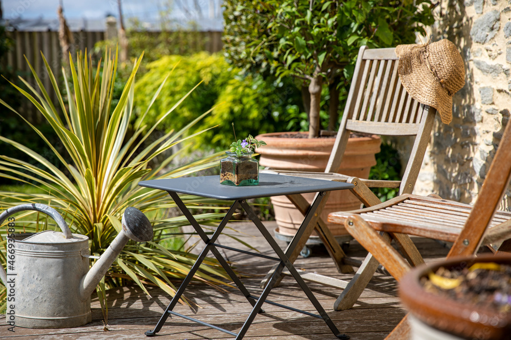 Obraz premium Chaise de jardin sur la terrasse en bois d'un jardinet au printemps.