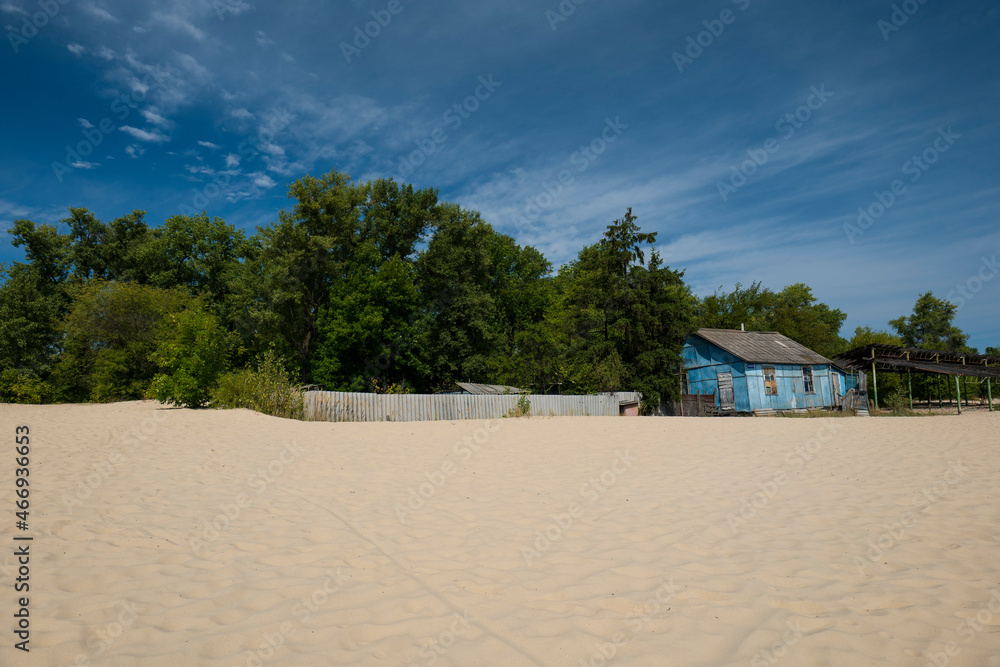 View across the beach to an old wooden house near a green forest. Relax in nature. summer landscape View across the beach to an old wooden house near a green forest. Relax in nature. summer landscape