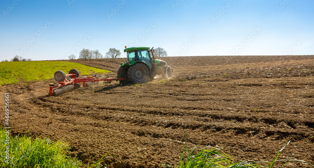 Fototapeta premium Tracteur retournant la terre dans un champ au temps des semences.