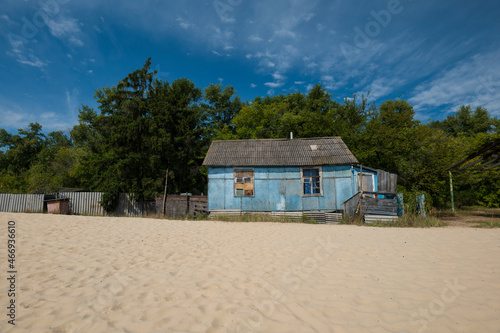 View across the beach to an old wooden house near a green forest. Relax in nature. summer landscape © YAROSLOVEPHOTOVIDEO