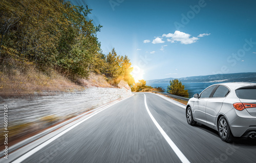 White car on a scenic road. Car on the road surrounded by a magnificent natural landscape.