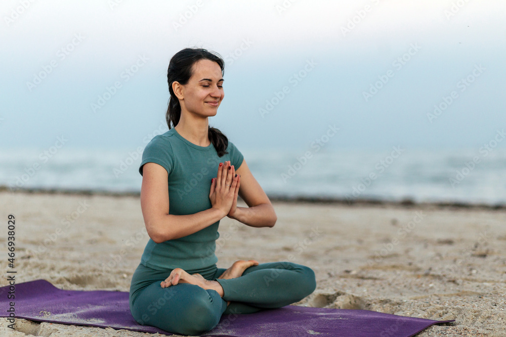 Young girl practicing yoga on the beach. Yoga, lotus pose, meditation and concentration.