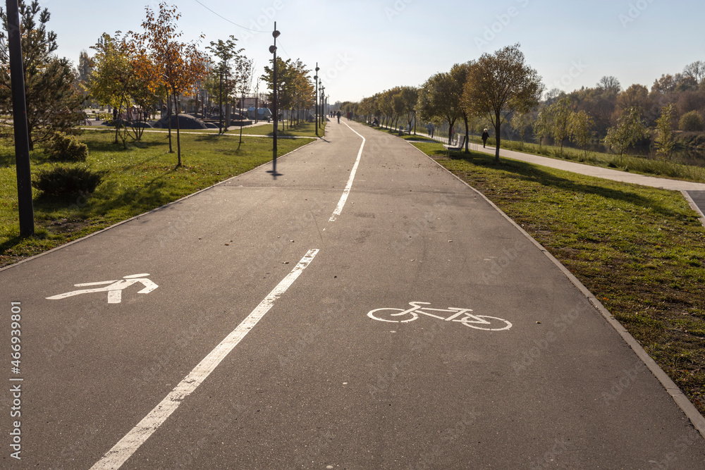 White road markings for pedestrians and cyclists.The walking and cycling paths in the park are separated from each other. Infrastructure for walking and physical activity in the park