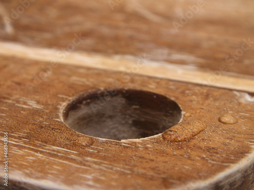 Loch im Holzbrett mit Wassertropfen etwas zerkratzt 