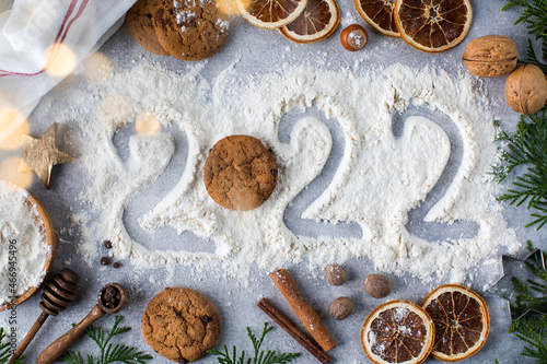  Christmas background with spices, cookies and painted number 2022 on flour. Happy New Year