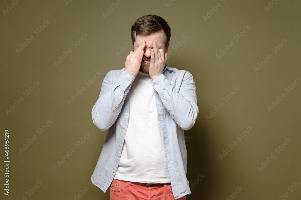 Man is depressed, he is unhappy and sobs, wiping the tears from his eyes with hands. Psychological health concept. Man is depressed, he is unhappy and sobs, wiping the tears from his eyes with hands. Psychological health concept.