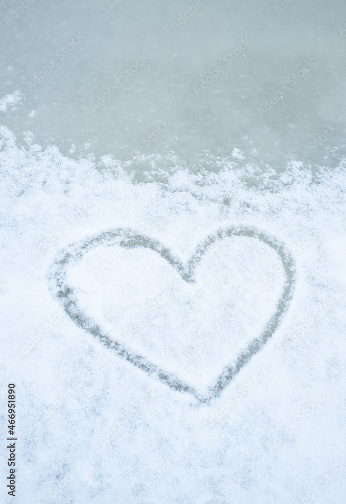 Love winter season. Heart shape drawn into snow on ice.