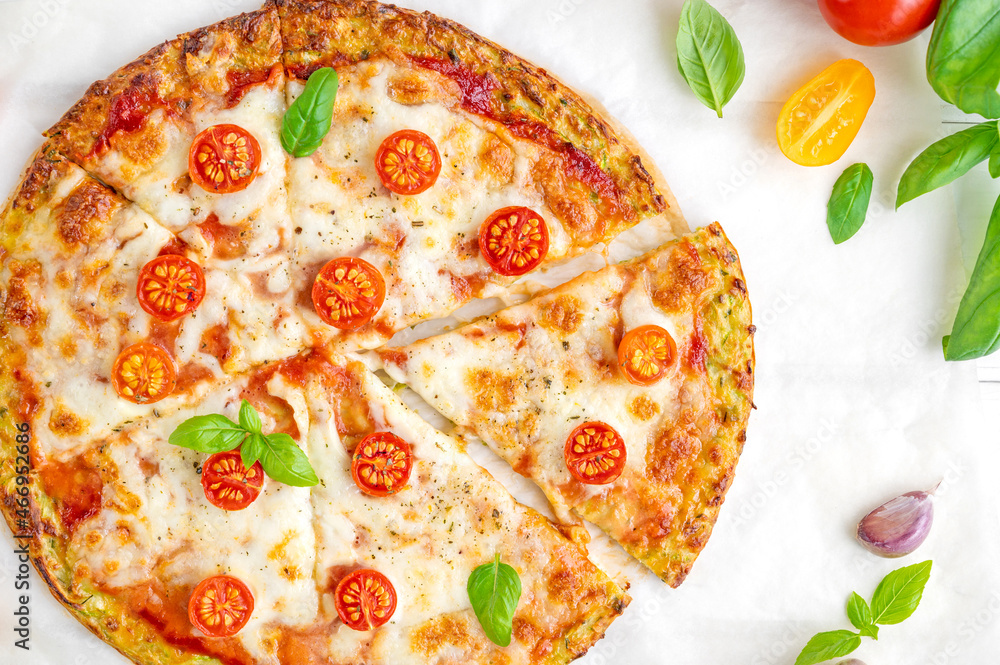 Zucchini crust pizza with tomato sauce, mozzarella cheese, fresh tomatoes and basil on a white wooden background. Zucchini pizza Margarita. Healthy dish.