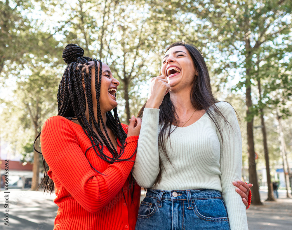 Laughing diverse friends standing on street Laughing diverse friends standing on street