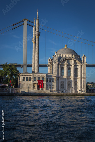 Exterior of the famous Ortakoy Mosque or Grand Imperial Mosque located right next to the Bosphorus Bridge in Ortakoy, with a Turkish flag hanging from one of it's walls.