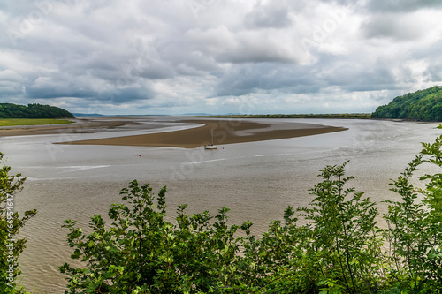 A view past trees over the mouth of the Taf estuary at low tide at Laugharne, Pembrokeshire, South Wales on a summers day