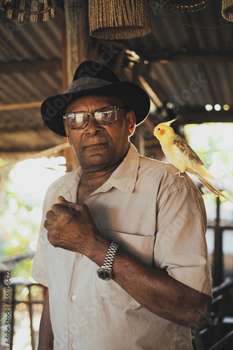 Stylish black man with cockatiel parrot on shoulder looking at camera photo