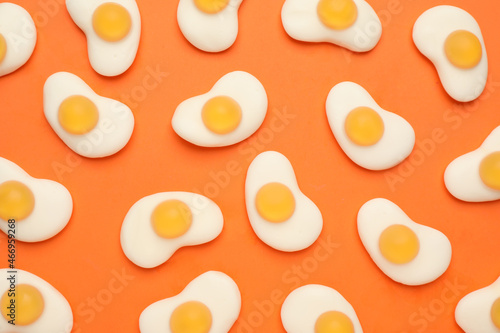 Foto Delicious gummy fried egg candies on orange background, flat lay