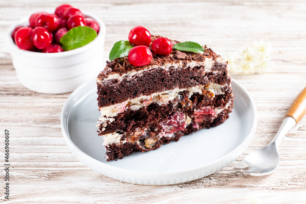 A piece of chocolate cake with cherry on plate on a wooden table. A piece of chocolate cake with cherry on plate on a wooden table.