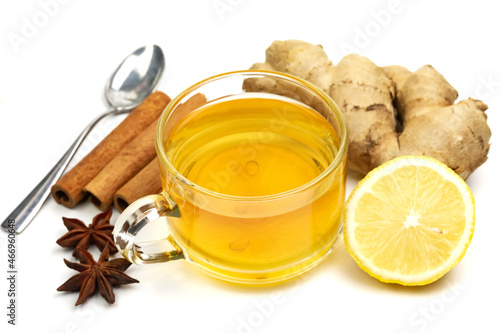 Glass of tea with ginger, lemon, cinnamon sticks and star anise isolated on white background.
