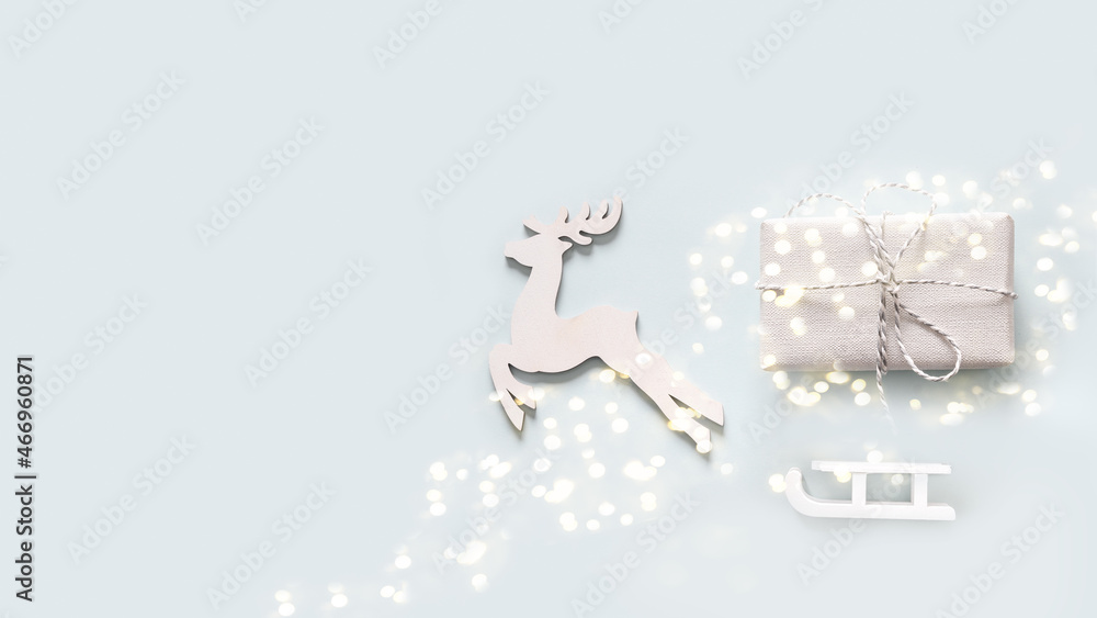Christmas greeting card with white reindeer, gift and sleigth on blue background. Banner. Flat lay with copy space. Christmas greeting card with white reindeer, gift and sleigth on blue background. Banner. Flat lay with copy space.