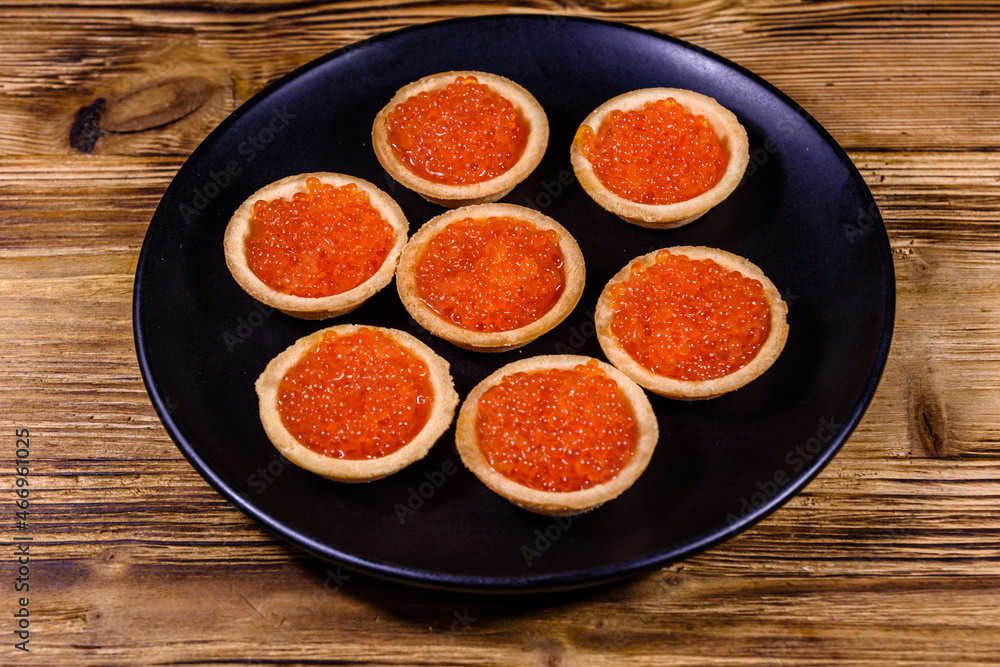 Tartlets with red caviar on a black plate. Festive food Tartlets with red caviar on a black plate. Festive food