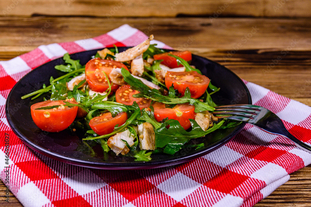 Roasted chicken breasts and salad with arugula and cherry tomatoes in a black plate Roasted chicken breasts and salad with arugula and cherry tomatoes in a black plate