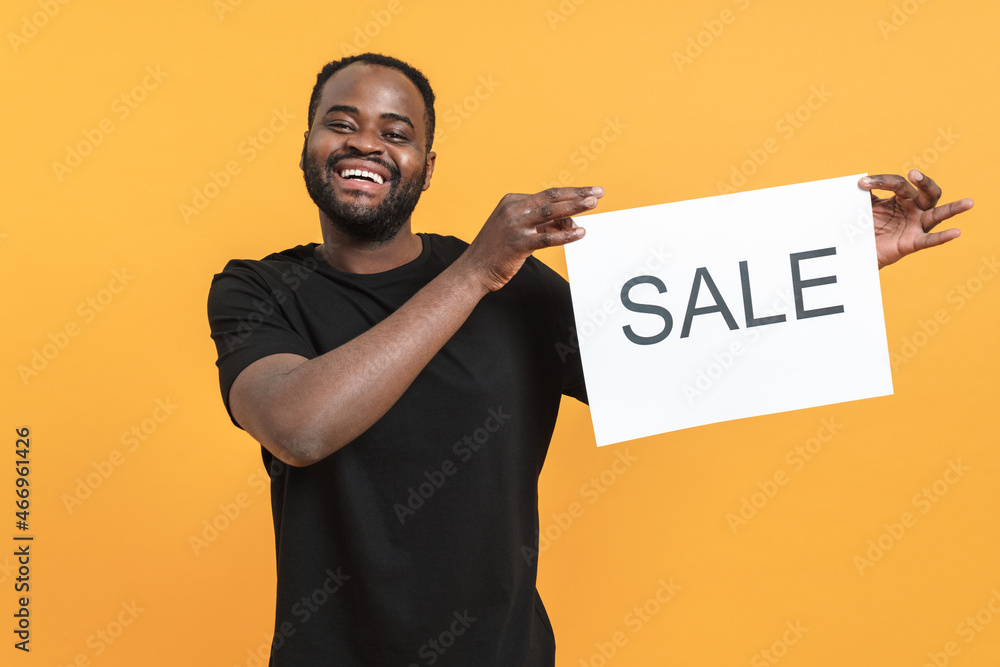 Black bearded man laughing while showing sale placard Black bearded man laughing while showing sale placard