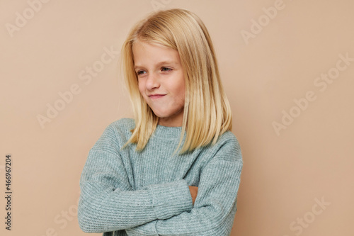 Beautiful little girl in a sweater, grimaces kids lifestyle concept