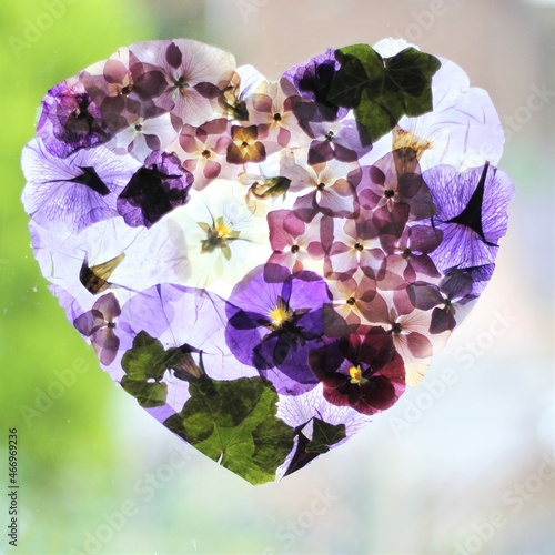 A pressed flowers heart , purple flowers , pansies, hydrangeas and ivy 