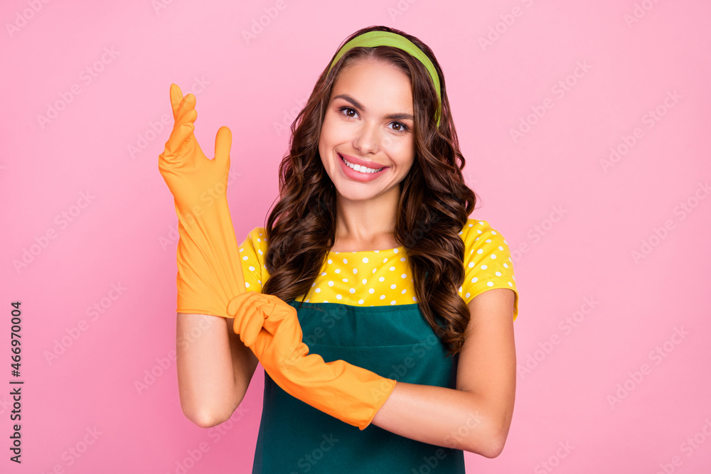 Photo of dreamy sweet young lady dressed green apron orange gloves ready cleaning smiling isolated pink color background Photo of dreamy sweet young lady dressed green apron orange gloves ready cleaning smiling isolated pink color background