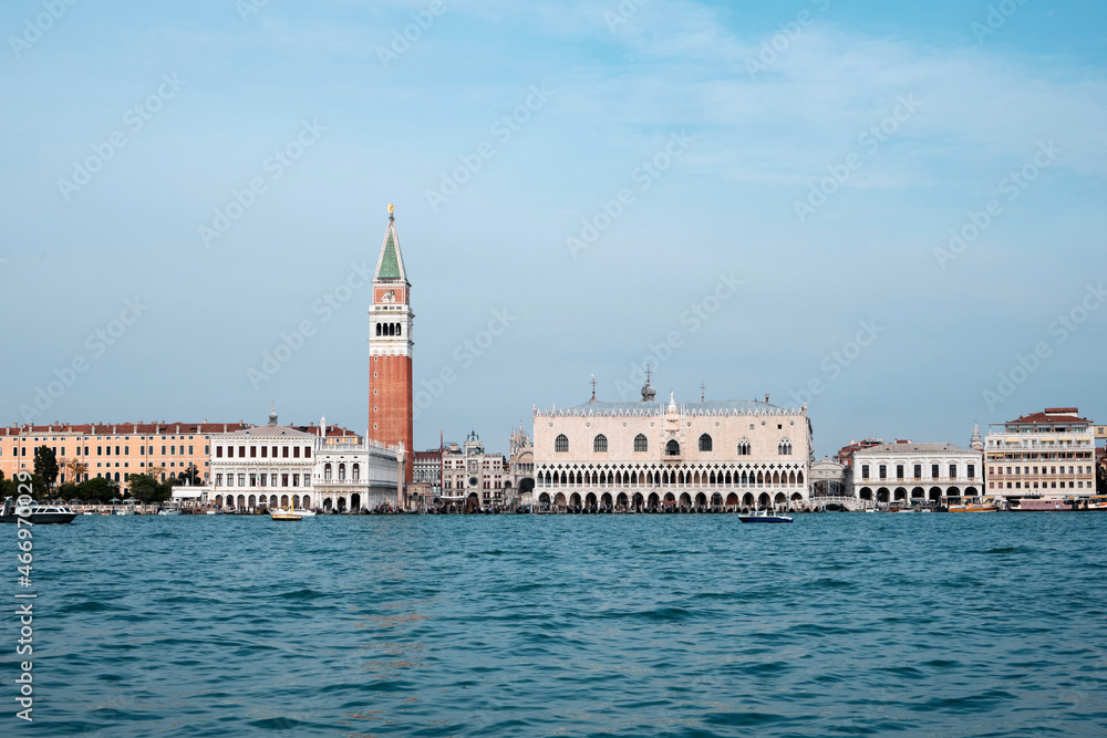Doge's palace and Campanile on Piazza di San Marco, Venice, Italy with reflection. View from passing vaporetto boat, with sea water of Venice Lagoon in front.