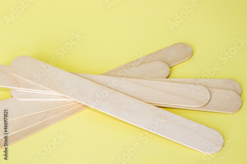 wooden sticks many spatula for depilation isolated on yellow background. close up view, sugaring pasta beauty salon,spa,hair removal,advertising banner free space for text photo