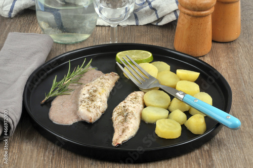 Filets de rougets-barbets en sauce avec des pommes de terre et une rondelle de citron servis dans une assiette posée sur une table photo