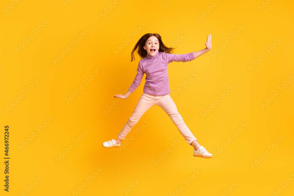 Full length body size view of attractive carefree cheerful girl jumping having fun fooling isolated over bright yellow color background Full length body size view of attractive carefree cheerful girl jumping having fun fooling isolated over bright yellow color background