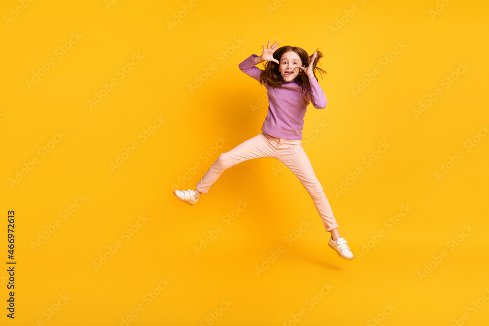 Full size photo of funky funny humorous little girl jumping fooling around showing tongue isolated on yellow color background Full size photo of funky funny humorous little girl jumping fooling around showing tongue isolated on yellow color background