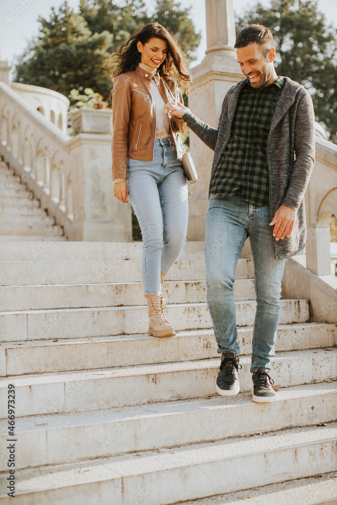 Young couple smiling and talking while strolling down outdoor stairs on autumn day