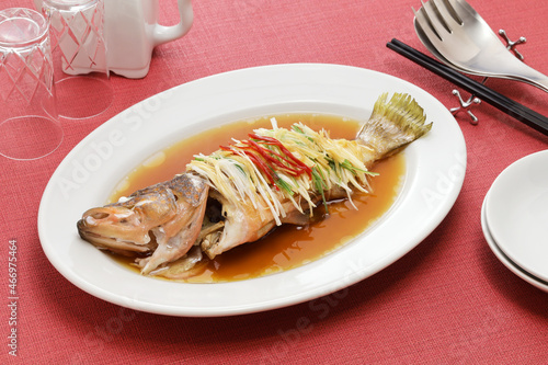 Chinese steamed whole Hong Kong grouper with scallion, ginger, and soy sauce photo