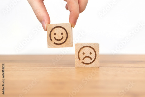 Customer hand choose smiley face icon on a woode cube. Service rating, satisfaction and marketing concept photo