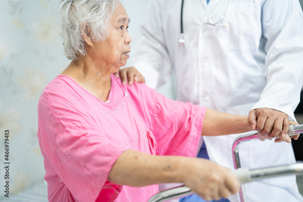 Fototapeta premium Asian nurse physiotherapist doctor care, help and support senior or elderly old lady woman patient walk with walker at hospital ward, healthy strong medical concept.