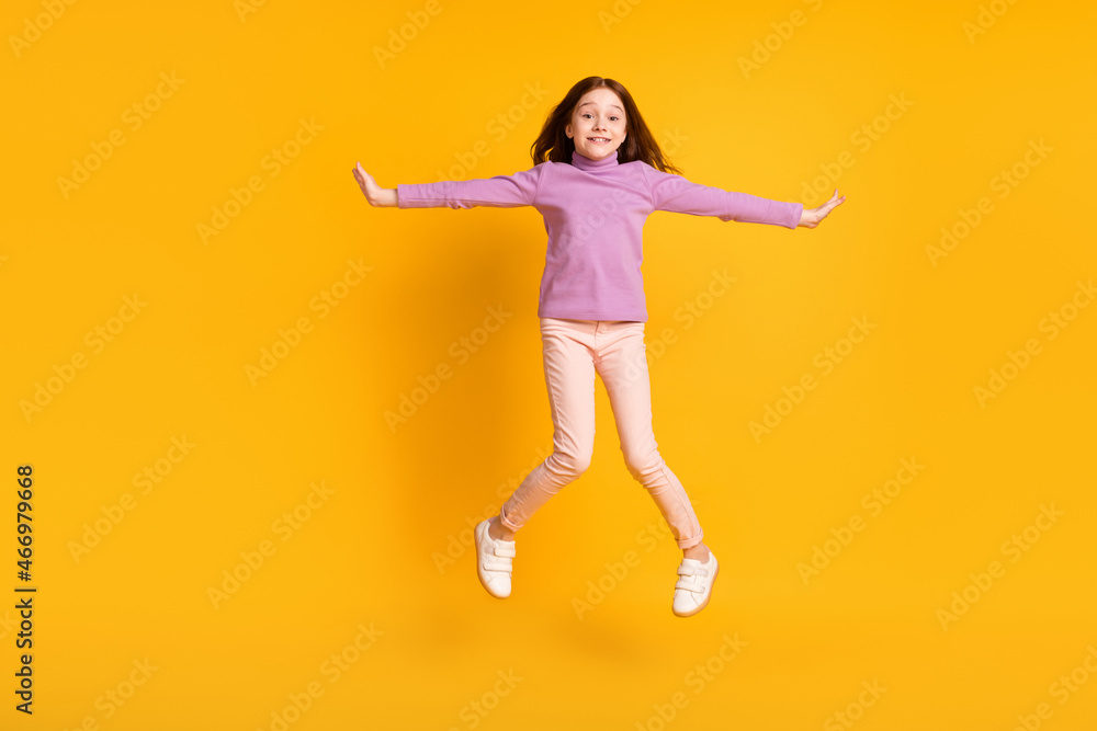 Full size photo of beautiful happy positive energetic little girl jumping having fun isolated on yellow color background