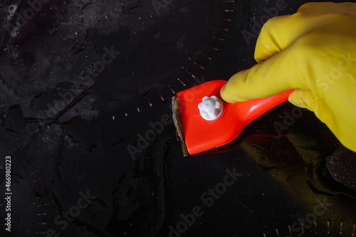 Scraper for cleaning glass ceramics against the background of a plate with burnt dirt