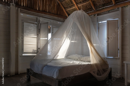 Interior of Mahaual Caribbean wooden hut, Mexican beach log cabin, dawn in bed whit mosquito net © Jon Ortiz