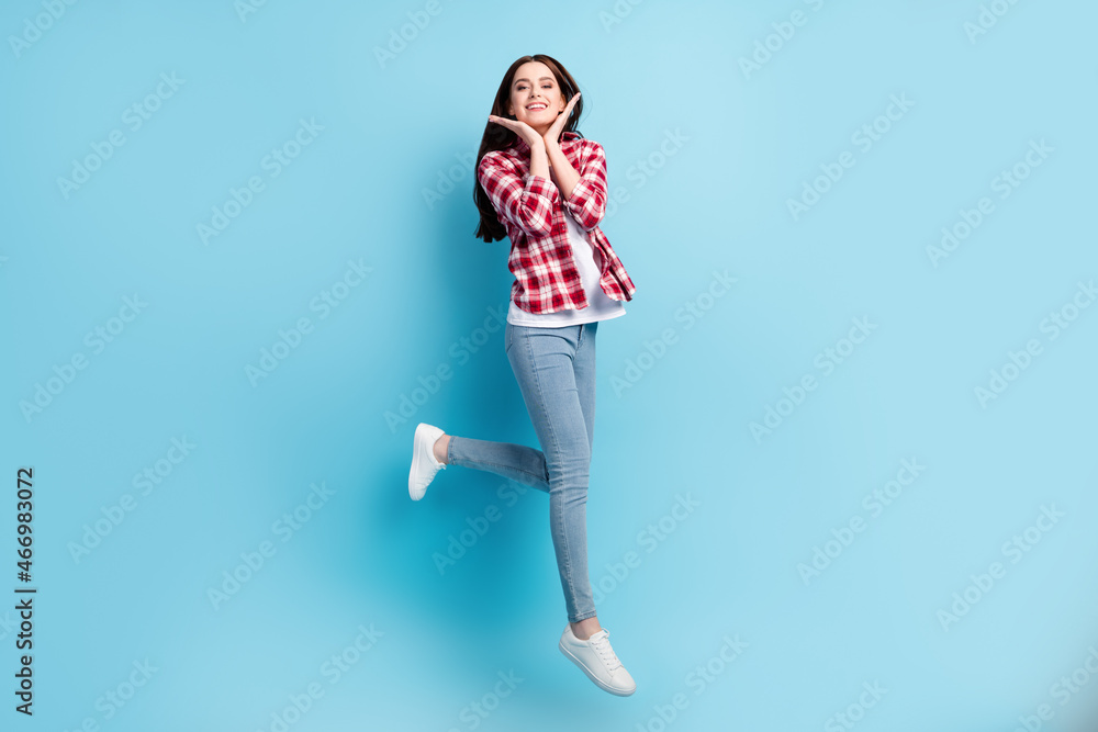 Full length photo of happy pretty positive woman hold hands face jump walk isolated on blue color background Full length photo of happy pretty positive woman hold hands face jump walk isolated on blue color background
