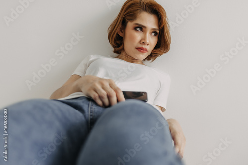 Asian woman resting and relax in the room with her smartphone in hand.