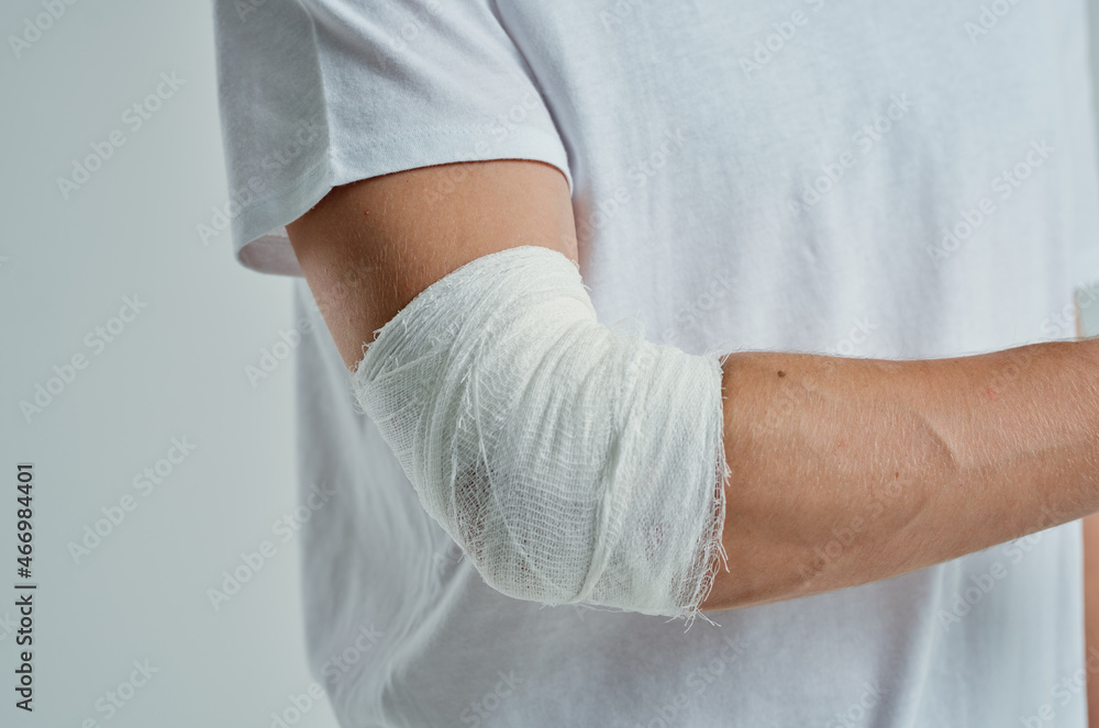 male patient in a white T-shirt with a bandaged hand light background