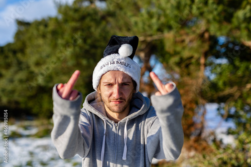 Fotografie A grumpy young man wearing a black santa hat with the words Bah Humbug written o