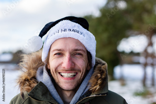 A ironic portrait of a smiling and happy young man wearing a black santa hat with the words Bah Humbug written on it photo