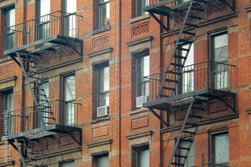 Photography Gritty exterior of orange brick  tenement style apartment building with black fi