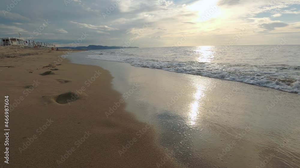 Handheld shot of beautiful calm waves lapping a sand beach in the quiet summer evening. Handheld shot of beautiful calm waves lapping a sand beach in the quiet summer evening.