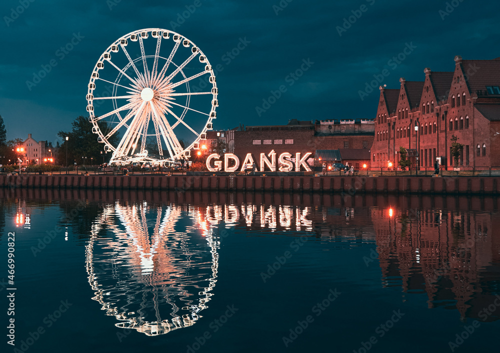 Reflection of the Ferris wheel in Gdansk, Poland. Old town center in the touristic city on the shore of the Baltic Sea in Poland. Beautiful night city lights - obrazy, fototapety, plakaty 